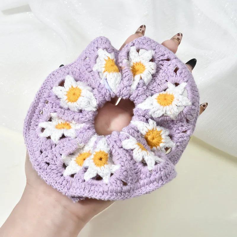 Handmade crochet product with floral pattern held by a hand on a white background