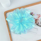 Iridescent blue scrunchie on a magazine with a blurred background