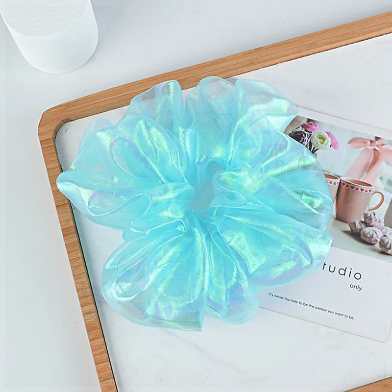 Iridescent blue scrunchie on a magazine with a blurred background