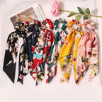 Colorful floral hair ties on a white surface with a magazine and pink flower.