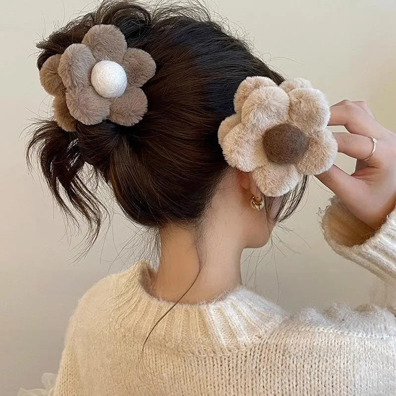 Person wearing fluffy flower-shaped hair accessories with a neutral background