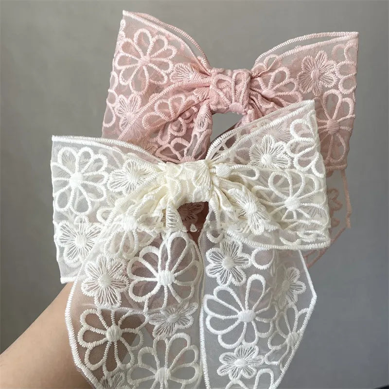 Two lace bows, one pink and one white, on a gray background.