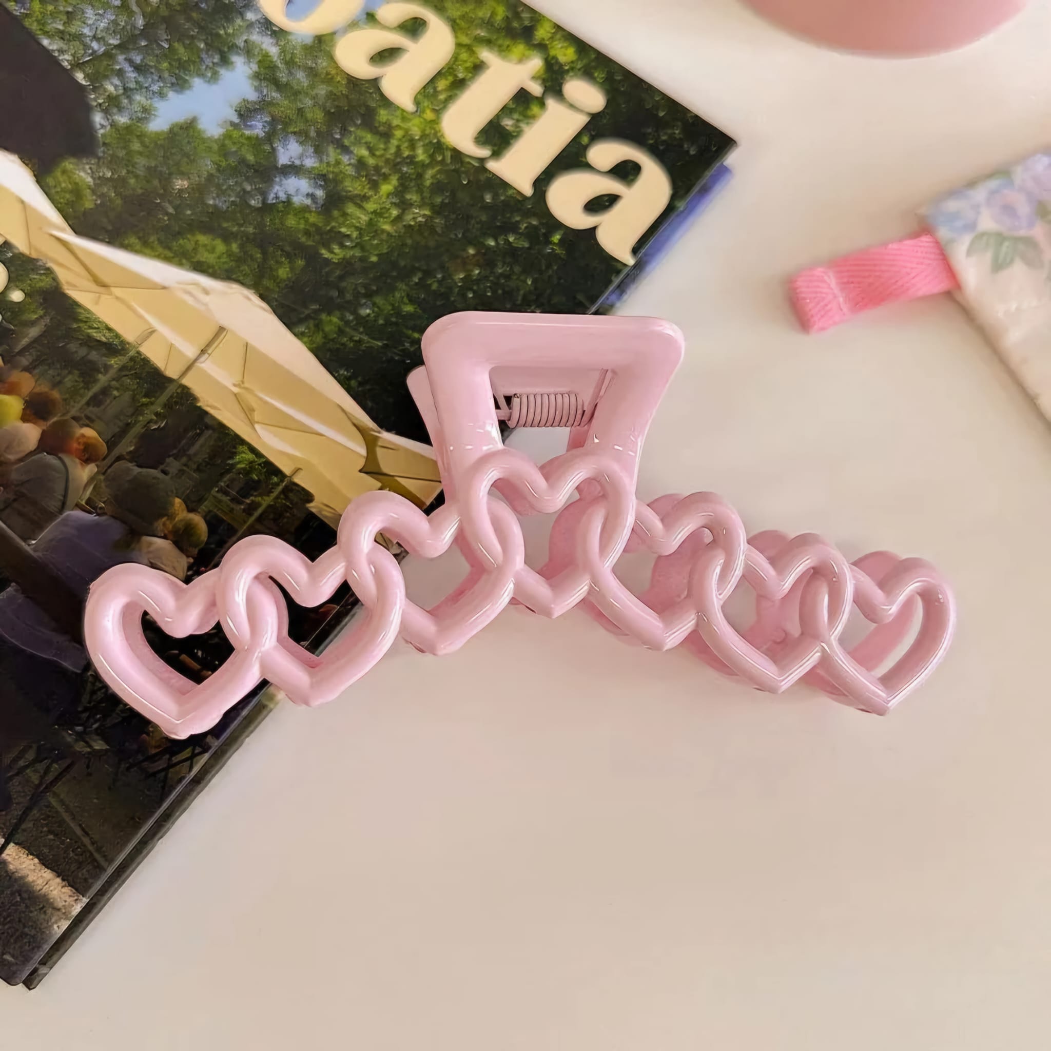Pink hair clip with heart designs on a surface
