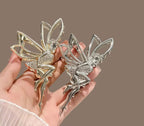 Silver fairy clip held in a hand against a brown background