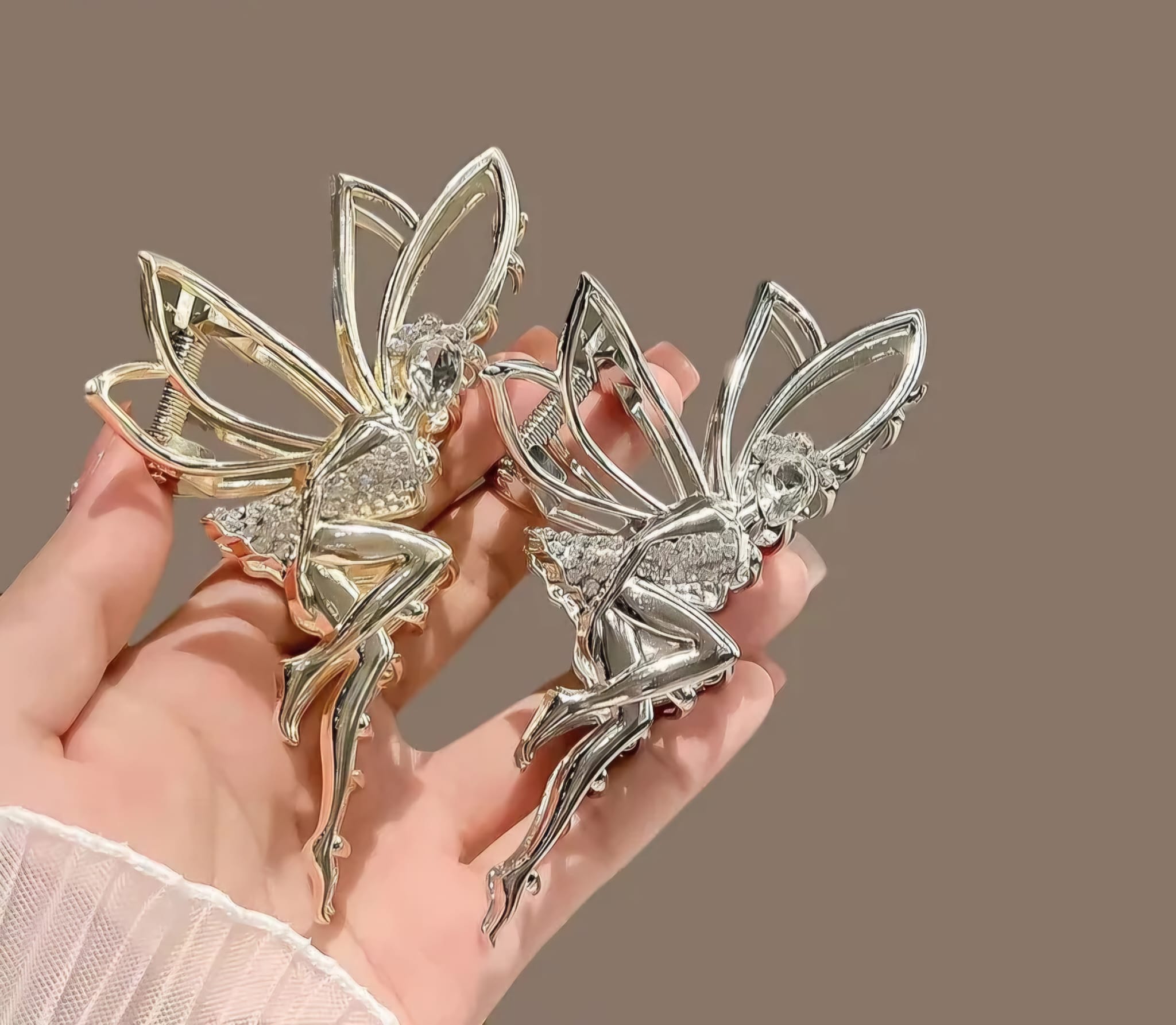 Silver fairy clip held in a hand against a brown background