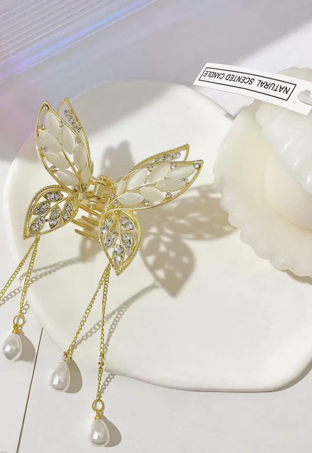 Gold butterfly hair clip with pearl details on a white surface