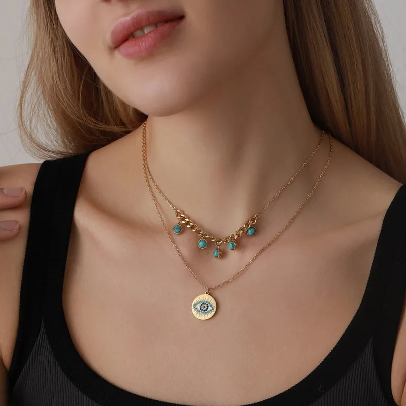 Close-up of a woman wearing a gold necklace with turquoise beads and an eye pendant.
