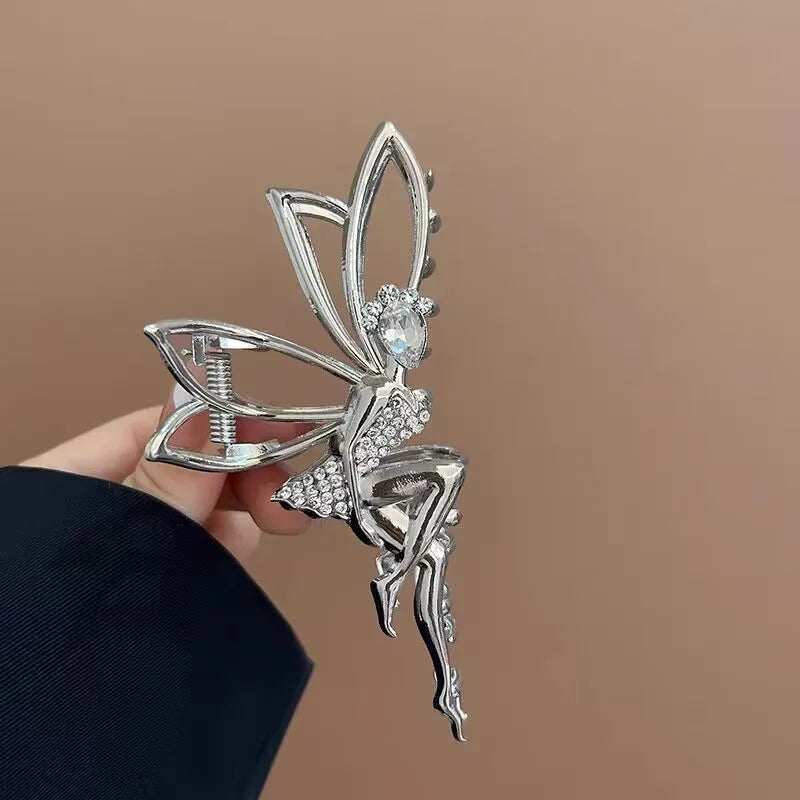 Silver fairy clip held by a hand against a brown background