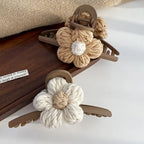Two knitted flower hair clips on a wooden tray with a white background